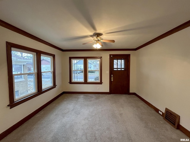 foyer entrance featuring light colored carpet, a wealth of natural light, crown molding, and ceiling fan