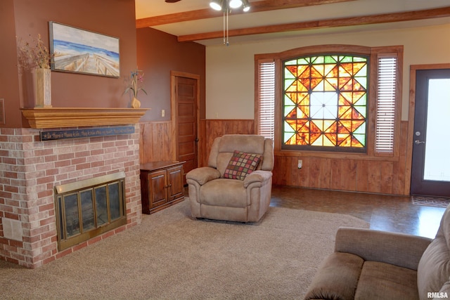 carpeted living room with a wainscoted wall, a fireplace, beam ceiling, and wooden walls