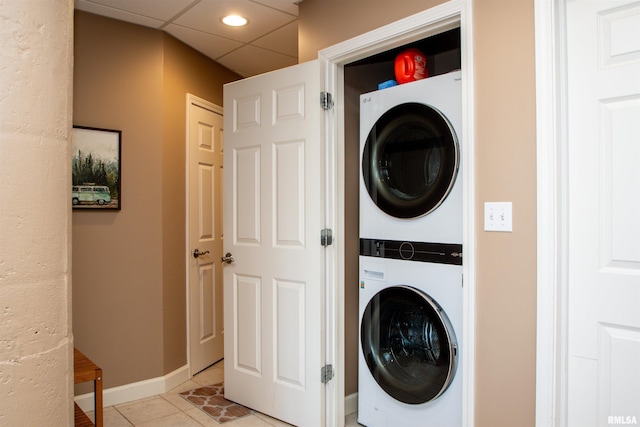 clothes washing area with light tile patterned floors and stacked washer / dryer