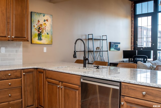 kitchen with kitchen peninsula, tasteful backsplash, light stone counters, sink, and dishwasher