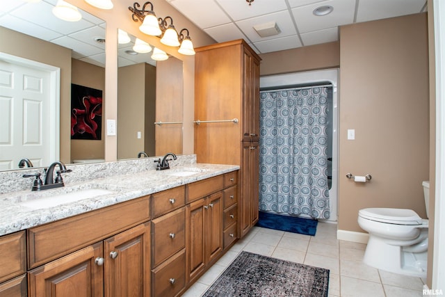 bathroom with a paneled ceiling, tile patterned flooring, vanity, and toilet