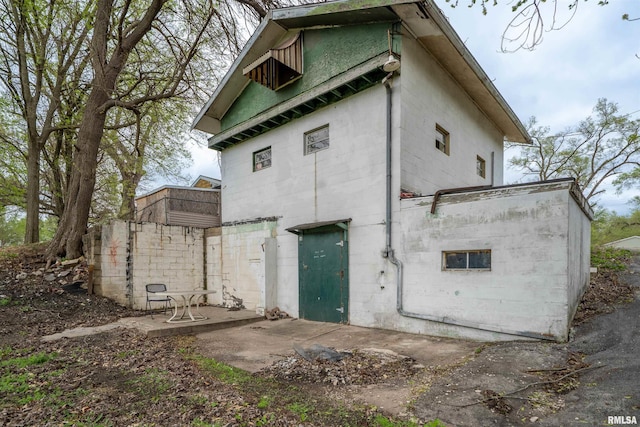 rear view of property with concrete block siding and a patio