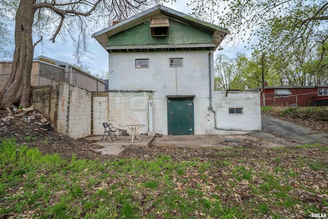rear view of property featuring concrete block siding and fence
