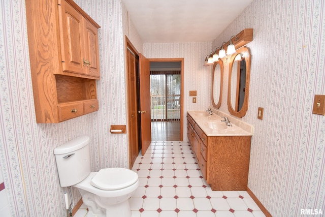 bathroom with double vanity, tile patterned floors, a sink, and wallpapered walls