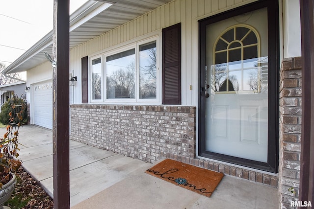 view of exterior entry with a garage and brick siding