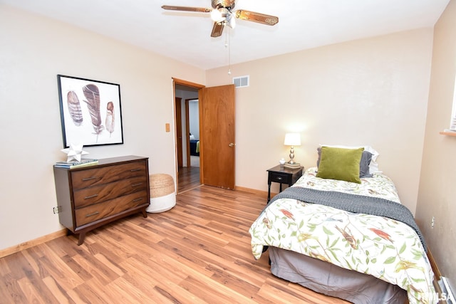 bedroom featuring a ceiling fan, light wood-style flooring, visible vents, and baseboards