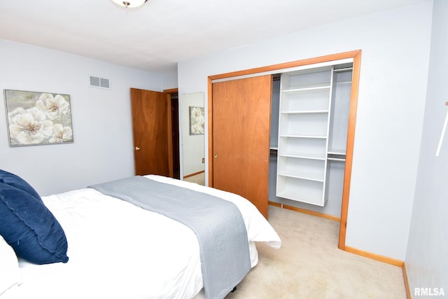 bedroom with baseboards, visible vents, a closet, and light colored carpet