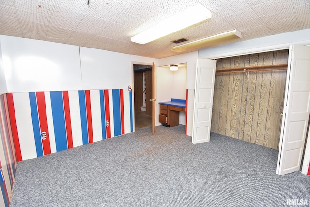 finished basement featuring dark colored carpet, visible vents, and wooden walls