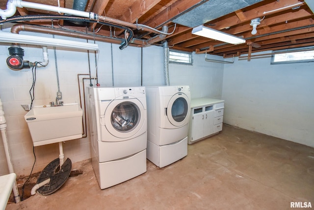 clothes washing area featuring a wealth of natural light, laundry area, independent washer and dryer, and a sink