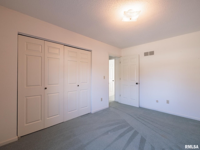 unfurnished bedroom with a textured ceiling, dark colored carpet, and a closet