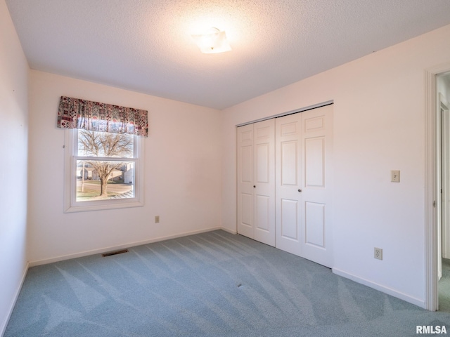 unfurnished bedroom featuring a closet, a textured ceiling, and carpet floors