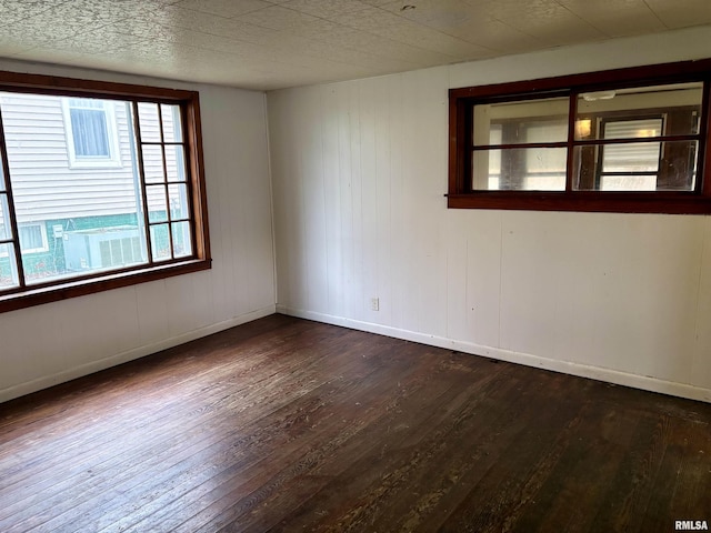 unfurnished room with dark hardwood / wood-style flooring and wooden walls