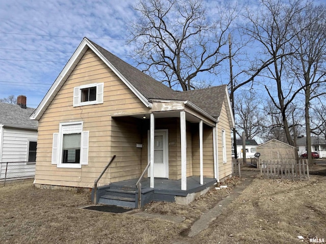 bungalow with a shingled roof and fence