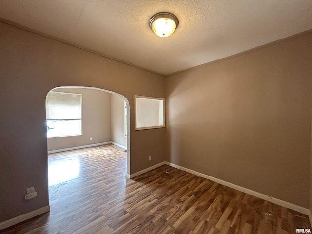 unfurnished room featuring dark wood-type flooring and a textured ceiling