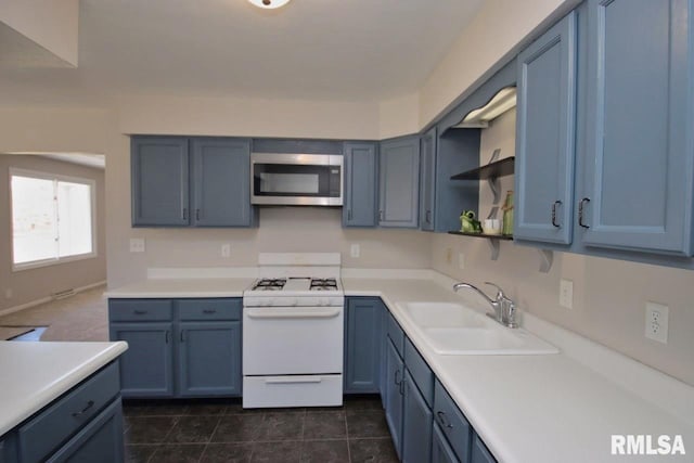 kitchen featuring blue cabinetry, sink, dark tile patterned flooring, and white stove