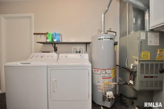 washroom with cabinets, heating unit, gas water heater, and washer and clothes dryer