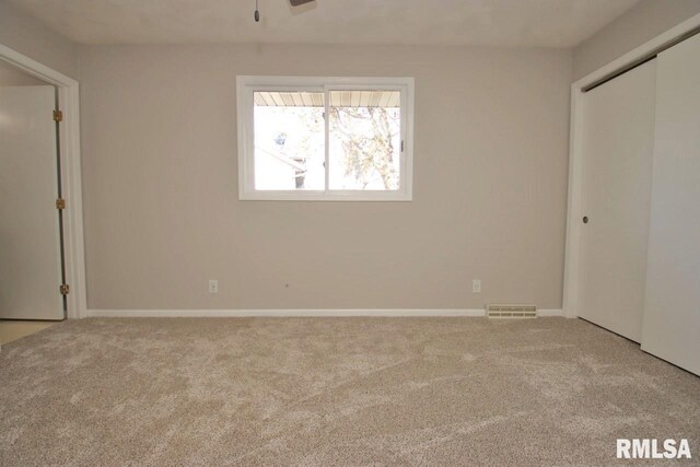 unfurnished bedroom featuring light carpet and a closet