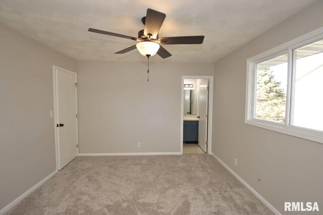 unfurnished bedroom with connected bathroom, light colored carpet, and ceiling fan