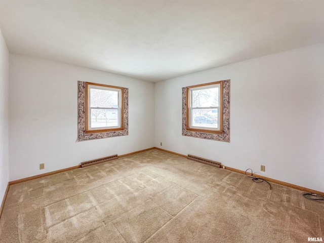 spare room with carpet floors, a baseboard radiator, and a wealth of natural light