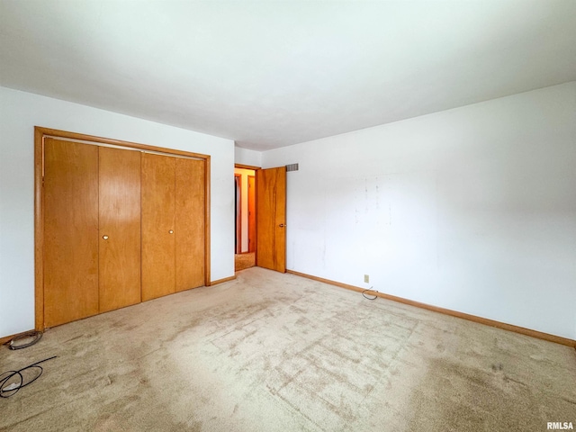 unfurnished bedroom featuring light colored carpet and a closet