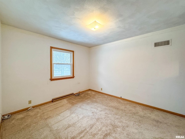 carpeted empty room with a textured ceiling and baseboard heating