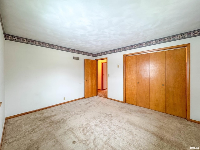 unfurnished bedroom with a closet and light colored carpet