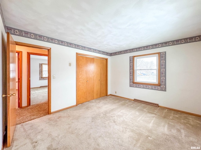 unfurnished bedroom with carpet floors, a baseboard radiator, and a closet