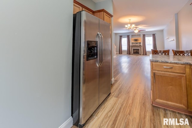 kitchen with light wood-type flooring, stainless steel fridge with ice dispenser, and a chandelier