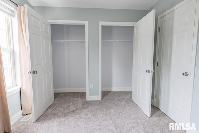 interior space with multiple windows, multiple closets, and light colored carpet