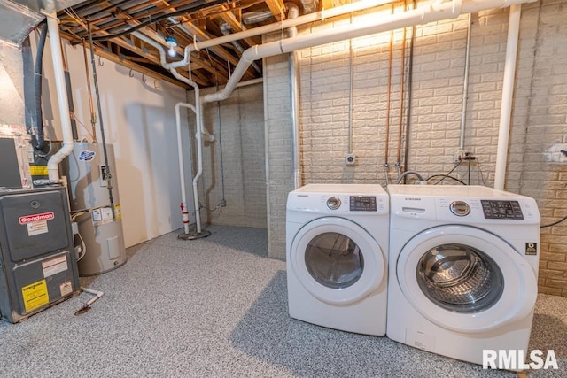 washroom featuring washing machine and dryer, electric water heater, and brick wall