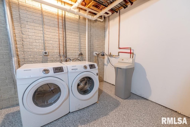 laundry area featuring washing machine and dryer and brick wall