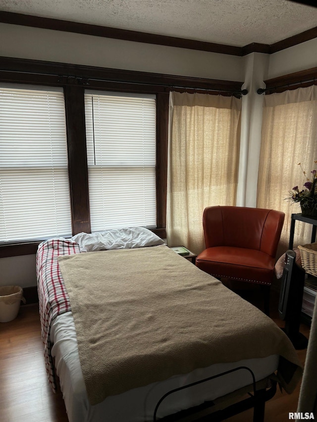 bedroom featuring hardwood / wood-style flooring, multiple windows, and crown molding