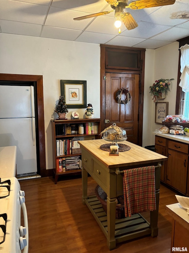 dining room with dark hardwood / wood-style flooring, a drop ceiling, and ceiling fan