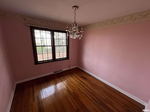 empty room with a chandelier and dark hardwood / wood-style flooring