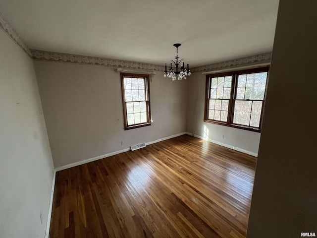 unfurnished room with hardwood / wood-style floors and an inviting chandelier