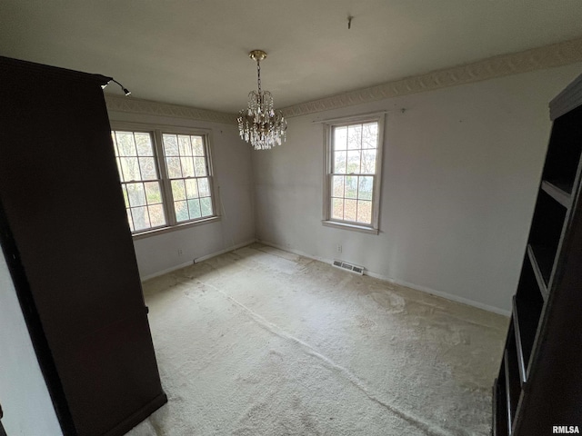 empty room featuring carpet and a notable chandelier