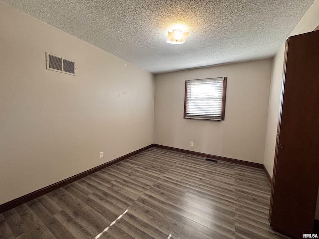 spare room featuring dark hardwood / wood-style flooring and a textured ceiling