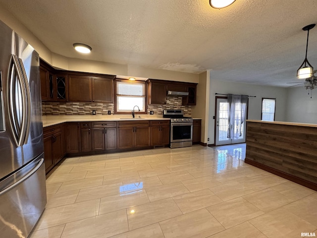 kitchen with a textured ceiling, backsplash, stainless steel appliances, and plenty of natural light