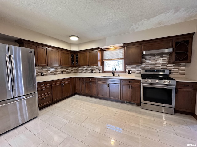 kitchen with backsplash, ventilation hood, sink, a textured ceiling, and appliances with stainless steel finishes