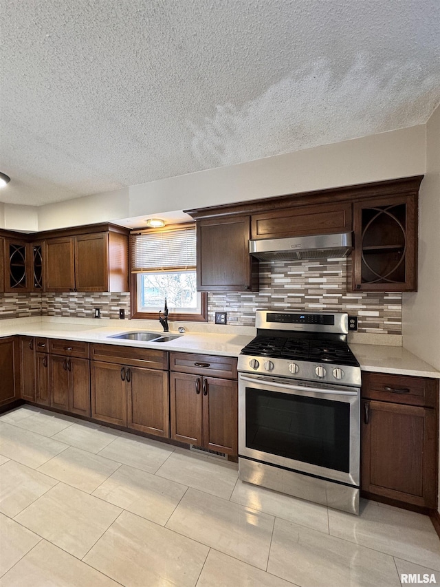 kitchen featuring a textured ceiling, sink, stainless steel stove, and dark brown cabinets