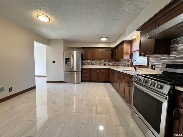 kitchen featuring exhaust hood, sink, a textured ceiling, tasteful backsplash, and stainless steel appliances