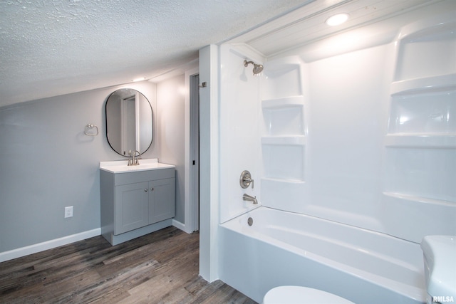 full bathroom featuring hardwood / wood-style floors, a textured ceiling,  shower combination, toilet, and vanity