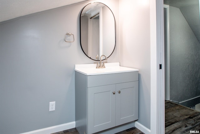 bathroom featuring hardwood / wood-style floors, vanity, a textured ceiling, and vaulted ceiling