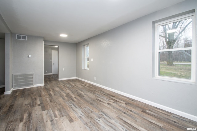 spare room with plenty of natural light and dark wood-type flooring