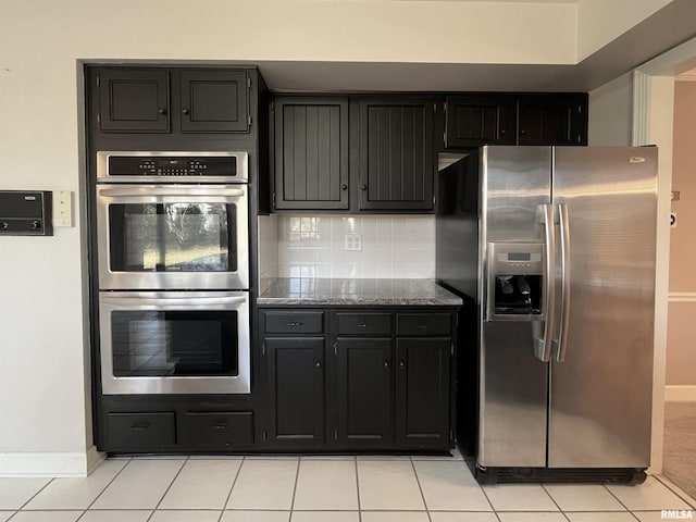 kitchen with backsplash, dark stone counters, light tile patterned flooring, and stainless steel appliances