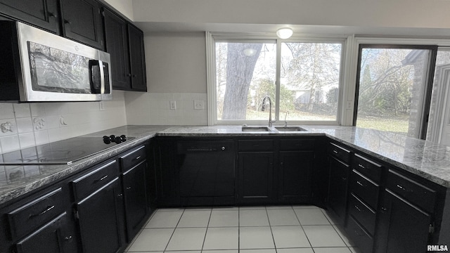 kitchen featuring light stone countertops, sink, backsplash, black electric cooktop, and light tile patterned floors