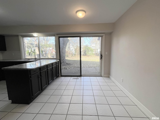 kitchen with dark stone countertops, sink, and light tile patterned floors