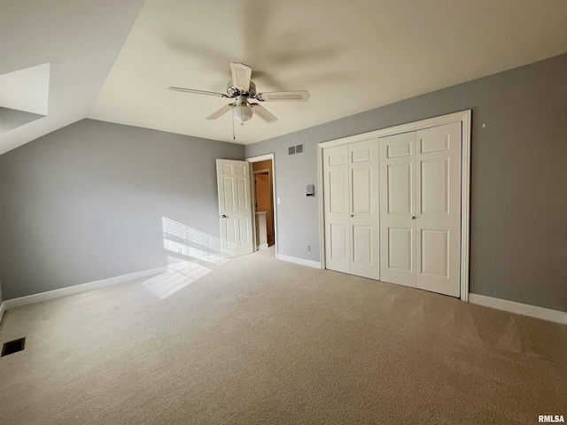 unfurnished bedroom with ceiling fan, a closet, carpet, and lofted ceiling