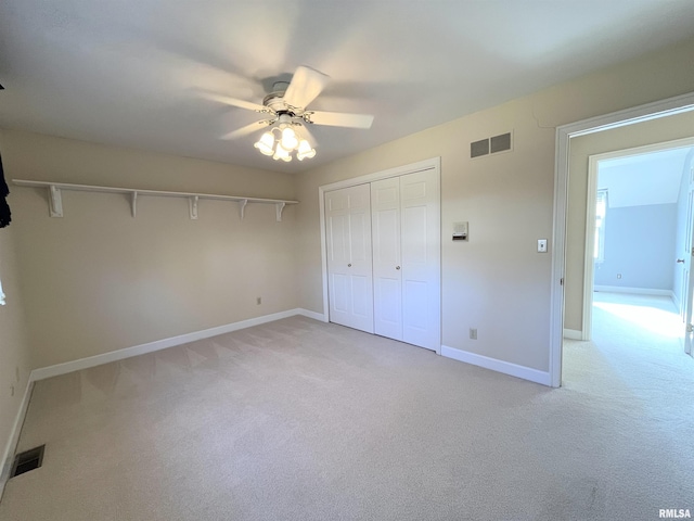 unfurnished bedroom featuring ceiling fan, light colored carpet, and a closet