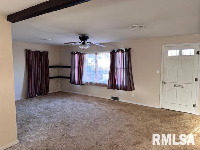 carpeted spare room featuring ceiling fan and beamed ceiling